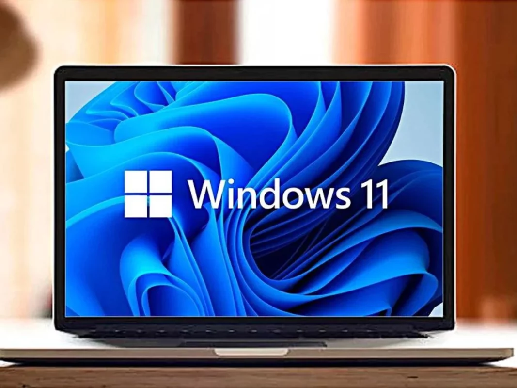 Portátil mostrando la pantalla de inicio de Windows 11 sobre una mesa